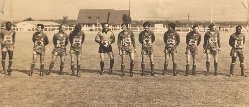 A yellowed photo of a soccer team, with a house in the background